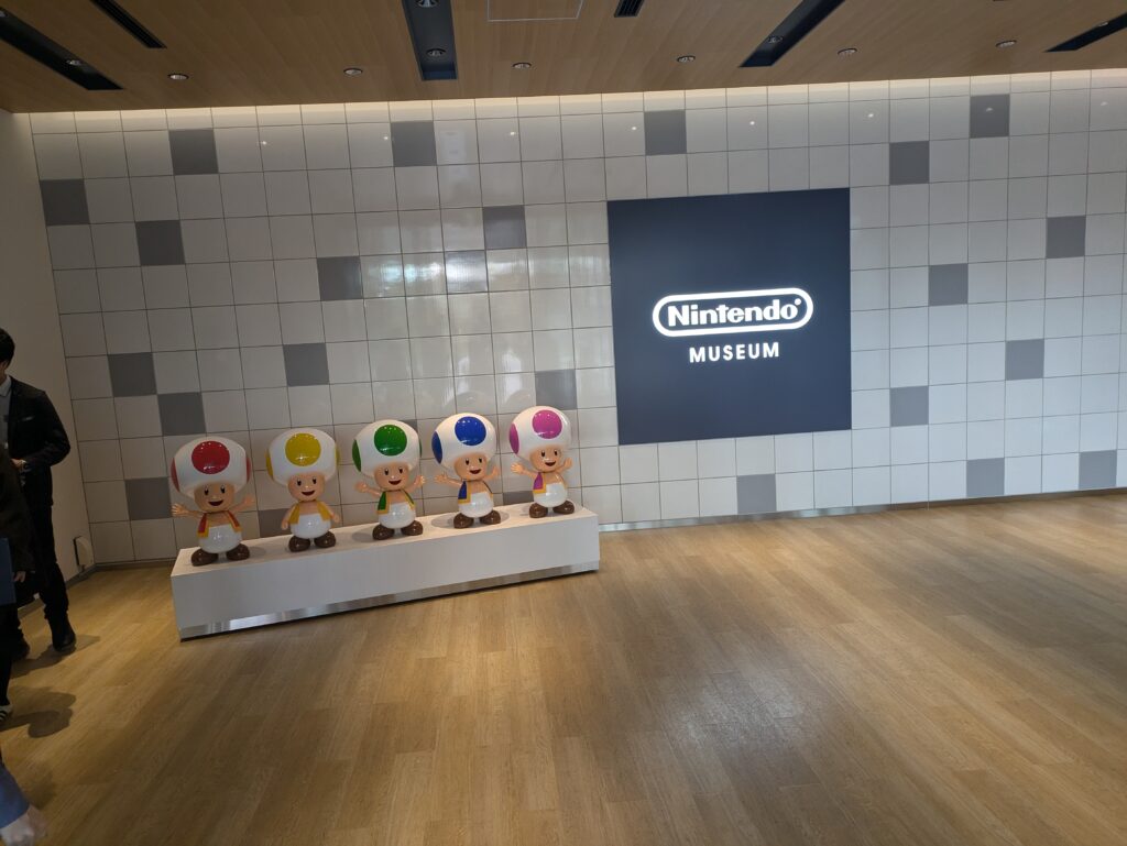 Cinco Toads coloridos na entrada interna do Nintendo Museum.