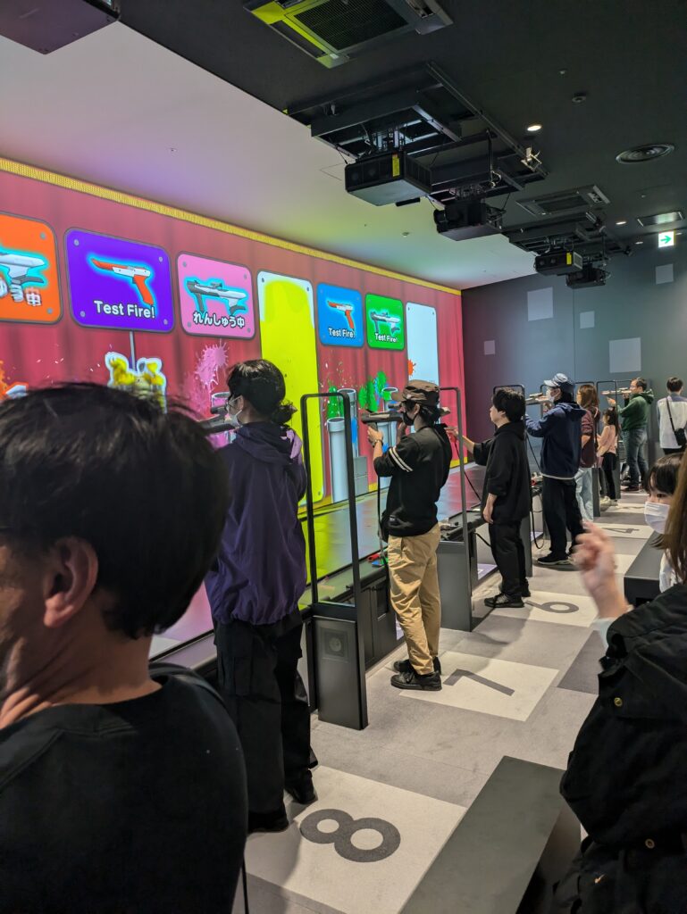 Visitantes usando Zapper e Super Scope na atração de tiro do Nintendo Museum.