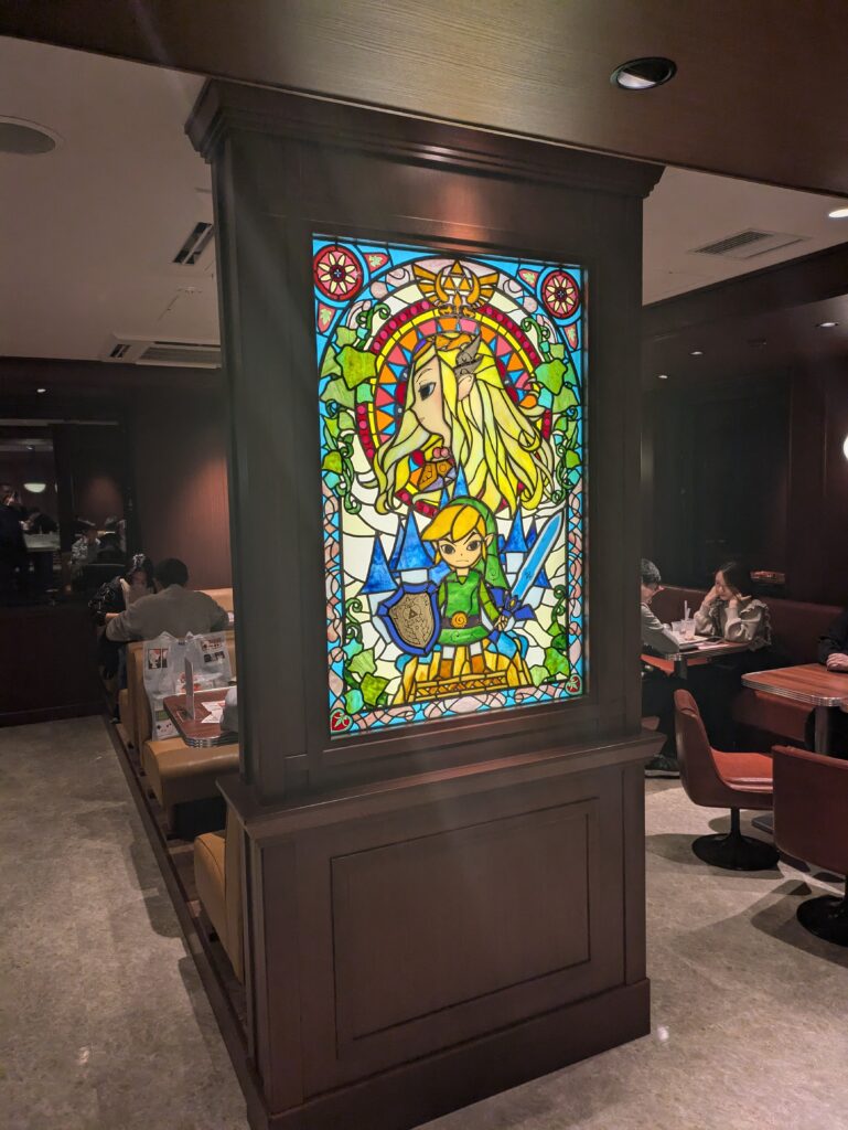 Vitral de The Legend of Zelda com Link e Zelda na área do café do Nintendo Museum.